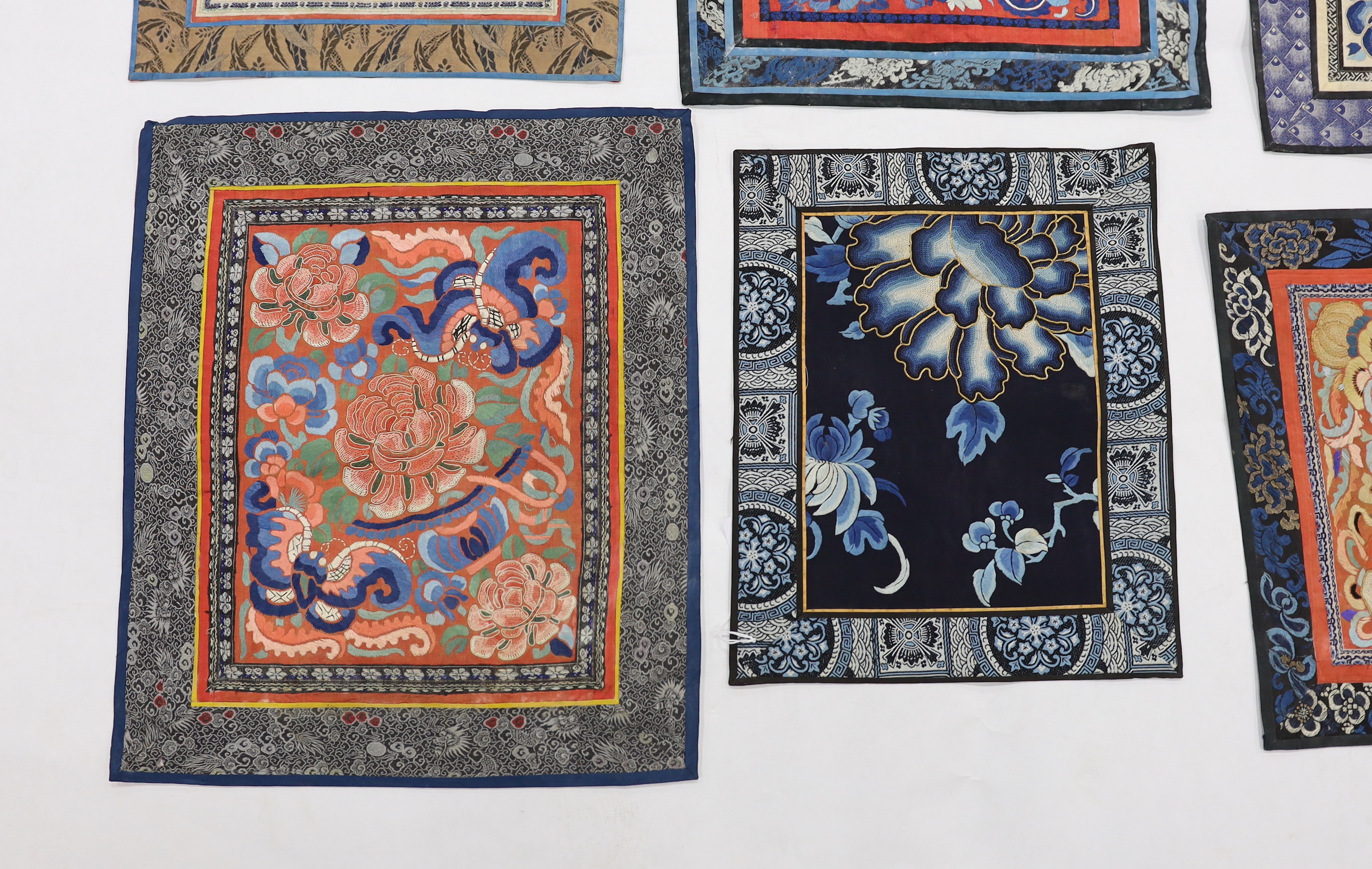 Six large Chinese silk embroidery mats with silk brocade borders, mostly embroidered flowers and butterflies in stem stitch and Beijing knot, largest 44.5cm x 37cm